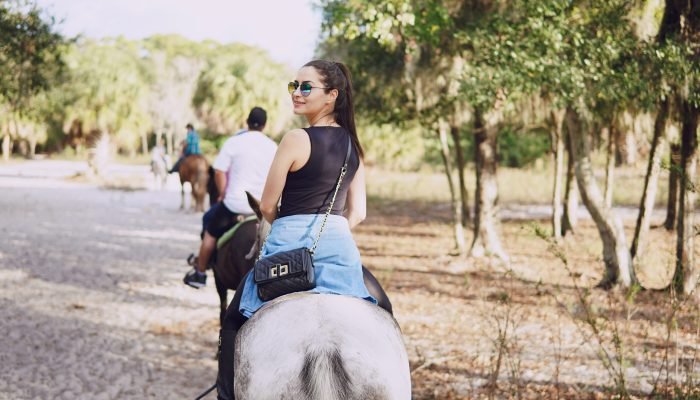 girl in sunglasses walking on the farm with horses